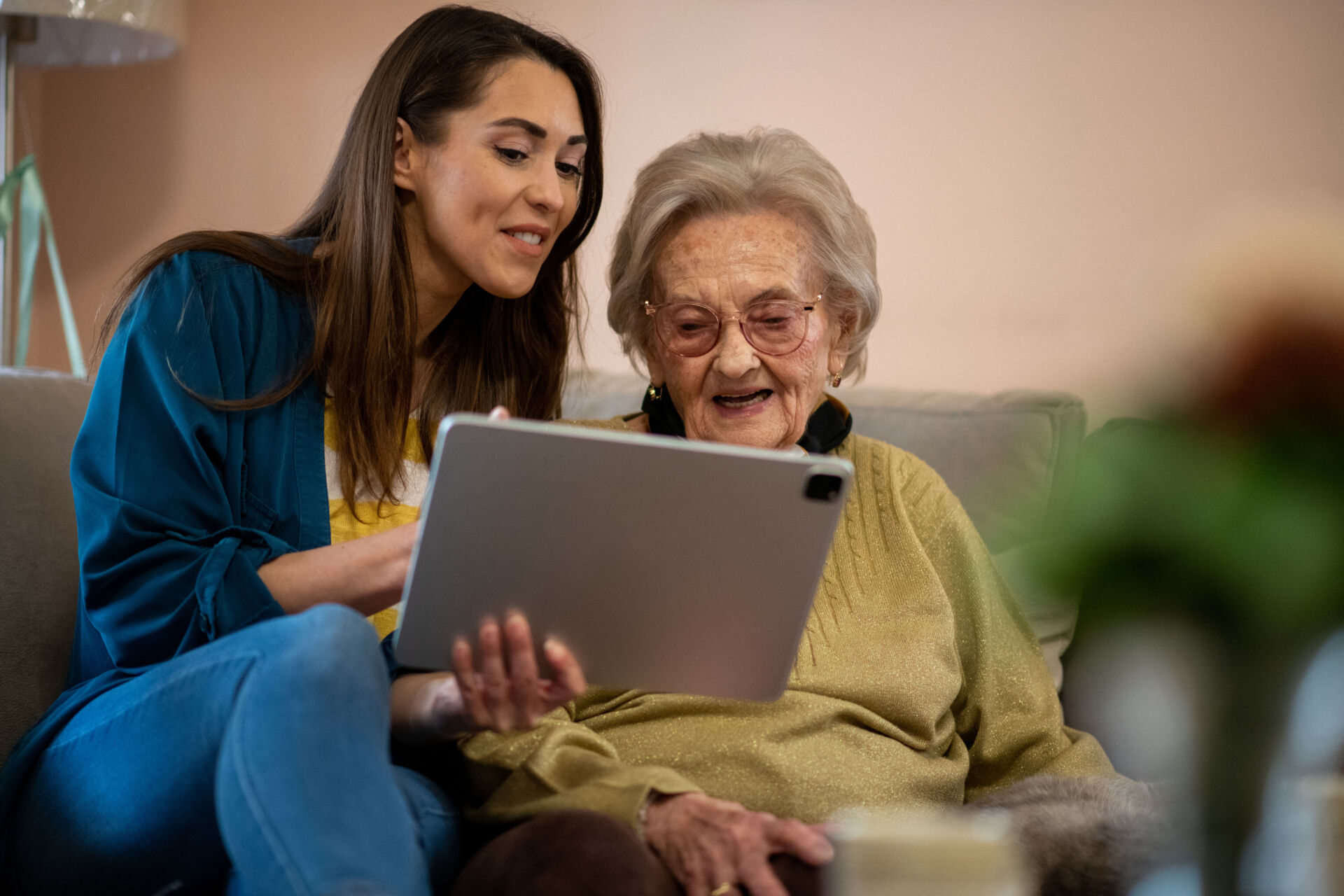 Senior woman and nurse using digital tablet to communicate with family members.